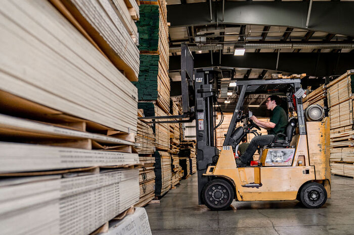 Forklift in warehouse lifting lumber products